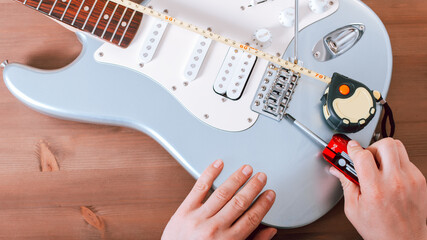 Guitar master adjusting bridge saddle on tremolo of electric guitar using multitool