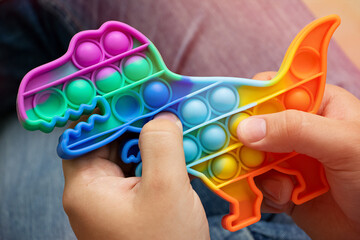 Anonymus adult hold in his hands new silcone toy pop it in shape of dinosaur.New sensory antistress...