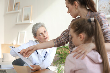 Obraz premium Mother and child in the doctor office meeting the pediatrician, they are sitting at desk in hospital.