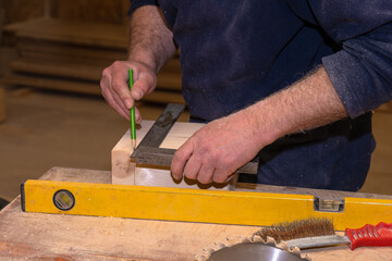 master carpenter measures the wooden billet with a ruler and marks it with a pencil. Production of handmade wooden products. Selective focus close-up