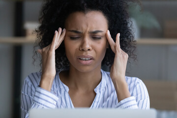 Close up of unhealthy tired young African American woman touch massage head struggle with migraine or headache. Exhausted biracial female suffer from dizziness or blurry vision. Overwork concept.