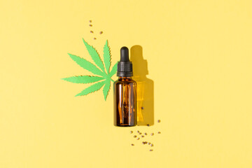 Cannabis oil extract in droplet bottle and seeds on yellow background top view. Medical marijuana cbd oil.