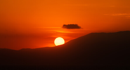 Photograph showing a sunset, in which the sun disappears from the mountains