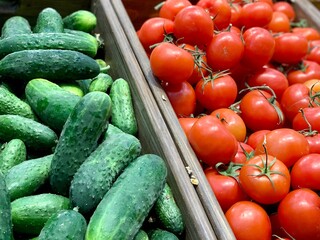 Cucumbers and tomatoes in a wooden box close-up.