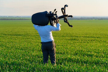 businessman carries an office chair in a field to work, freelance and business concept, green grass and blue sky as background