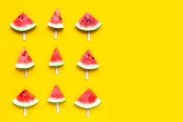 Watermelon slice popsicles on yellow background.