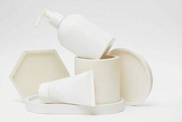  White various bottles with a cosmetic product on a background of geometric shapes. Podium with cosmetics. 