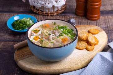 Soup with chicken, noodles, potatoes, quail eggs and carrots. Seasoned with onions and parsley. Close-up.