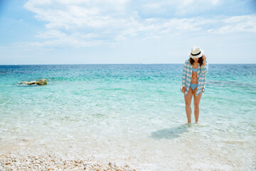 woman in blue checked shirt walking by sea beach
