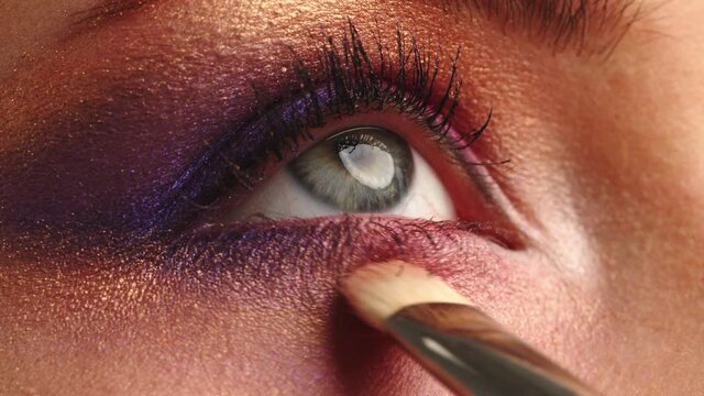 Make-up artist applies makeup to the upper eyelid, close-up.  Makeup artist applies a bright eye shadow with a makeup brush.Tutorial master class of professional makeup. Slow motion cinematic shoot.