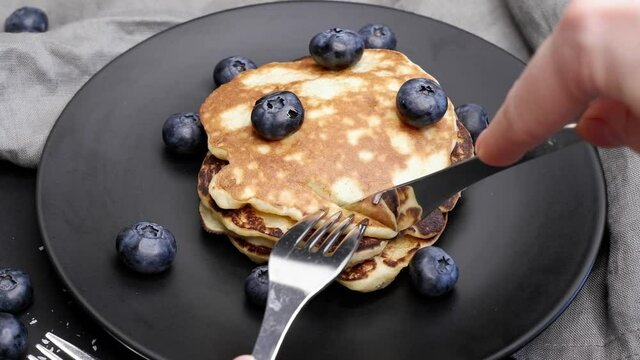 The girl eats pancakes with blueberries.