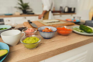 Ingredients for sushi and rolls on a kitchen table. Rice, red pickled ginger, cucumber, crab meat, salmon fish fillet. Professional sushi making