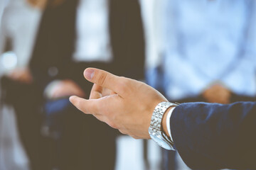 Business man making presentation to group of people, close-up. Speaker delivering a seminar to his colleagues or business training in office. Teamwork and coaching concept