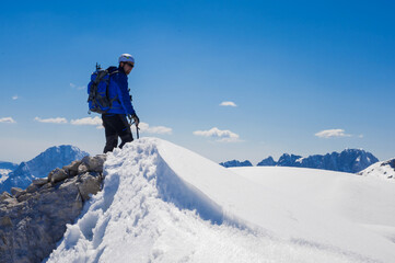 Fototapeta na wymiar climber on the top of the alpine mountain Mala Mojstrovka against the backdrop of snowy alps