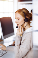 Businesswoman talking by headset in office. Call center and diverse people group in business