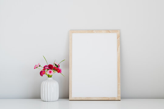 Vertical wooden frame mockup and vase with fresh flowers on white background. Minimal style.