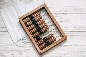 wooden abacus with medical masks on a white background. Treatment cost concept.