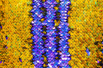 The shiny bright texture of the sequins changes color. Purple and yellow. Fabric for fancy dresses.