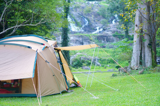 camping tent on nature waterfall with tree in green garden or forest by family camper for holiday relax and vacation travel trip to trekking picnic on meadow grass at khlong nam lai waterfall campsite