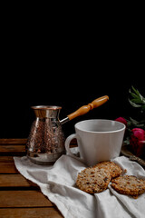 turk with coffee, black coffee cup, red flowers, cookies, lemon, wooden table, black background