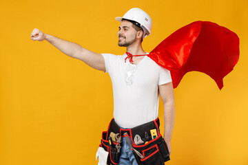 Powerful employee handyman man in red superhero suit helmet hardhat makes fly gesture isolated on yellow background studio Real heroes defend you. Instruments renovation apartment room Repair concept.