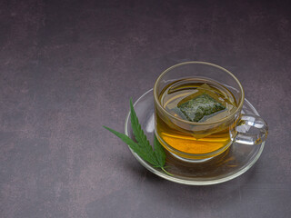 A cup of hemp tea and marijuana leaf laid on vintage background. Cannabis herbal tea. Close-up photo. Selective focus. Relaxation concept