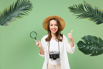 Traveler tourist woman in casual clothes hat use magnifier loupe show thumb up isolated on pastel...