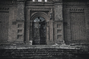 An old beautiful and scary abandoned church. Brick walls. Gloomy gothic atmosphere. Evening light.