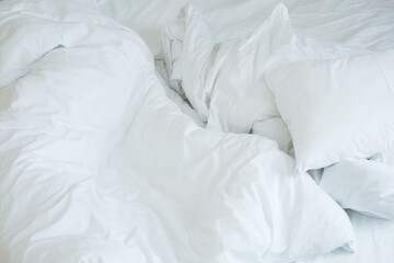 Crumpled bed, pillows and blankets. Close-up of unfinished or messy bed after funny night