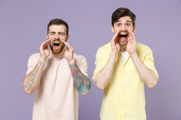 Two expressive young men 20s friends together wearing casual t-shirt tattoo translate fun shout...
