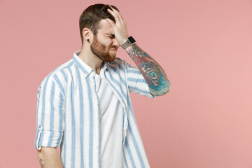 Young ashamed caucasian unshaven man 20s wear blue striped shirt put hand on face facepalm epic fail mistaken omg gesture isolated on pastel pink background studio portrait. People lifestyle concept. - obrazy, fototapety, plakaty