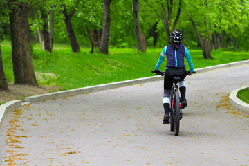 Young woman riding a bicycle in the park. Healthy lifestyle, people riding bicycle in city park