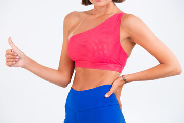Fit tanned sporty woman with abs, fitness curves, wearing top and blue leggings on white background