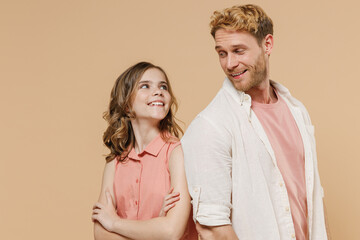Young parent man have fun with child teen girl in casual pastel clothes. Daddy little kid daughter look to each other stand back to back isolated on beige background. Father's Day Love family concept.