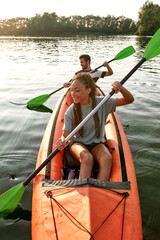 Adventurous young girlfriend paddling kayak on a river together with her boyfriend on a summer afternoon © Svitlana