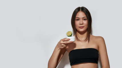 Happy young asian woman holding citrus and cream