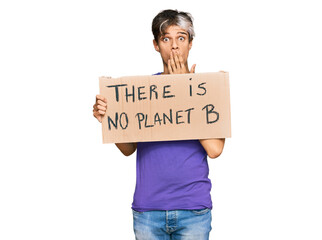 Young hispanic man holding there is no planet b banner covering mouth with hand, shocked and afraid for mistake. surprised expression