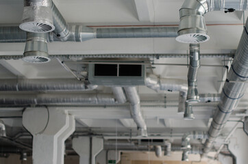 Ventilation pipe in silver insulation material hanging under the ceiling. Air conditioning of buildings. 