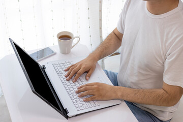 自宅のテーブルでパソコン作業をする男性のイメージ（若い、30代、日本人）