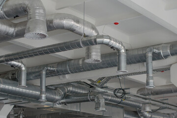 Air duct, air conditioner pipe and fire sprinkler system on white ceiling. Air flow and ventilation system. Building interior. Interior architecture concept.