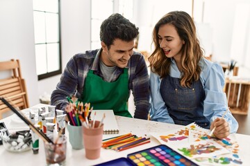 Fototapeta premium Two students smiling happy painting sitting on the table at art school.