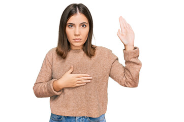 Young beautiful woman wearing casual clothes swearing with hand on chest and open palm, making a...