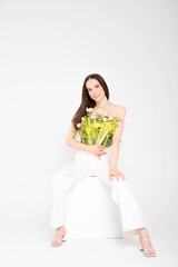 The girl is a brunette model, posing with a vegetable and flower bouquet in her hands.