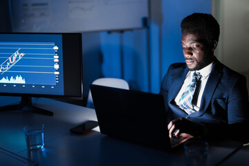 African man trader working at night time inside hedge fund bank office - Trading, investment and...
