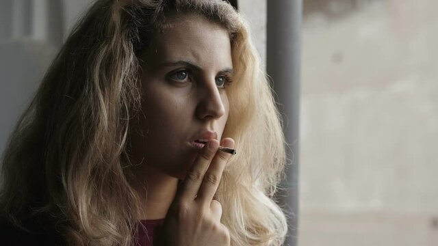 serious beautiful woman smokes a cigarette looking away lost in her thoughts