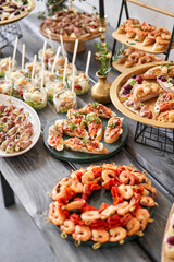 Delicious fresh seafood, shrimp with fresh vegetables. buffet table with lots of delicious snacks. canapes, bruschetta, and little desserts on wooden plate board