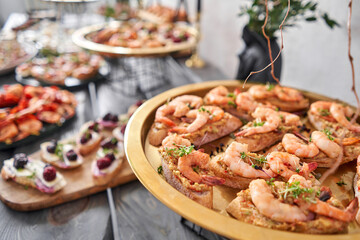 Delicious bruschetta with salmon and canape shrimp on table. Tasty buffet table. Summer party. Catering concept