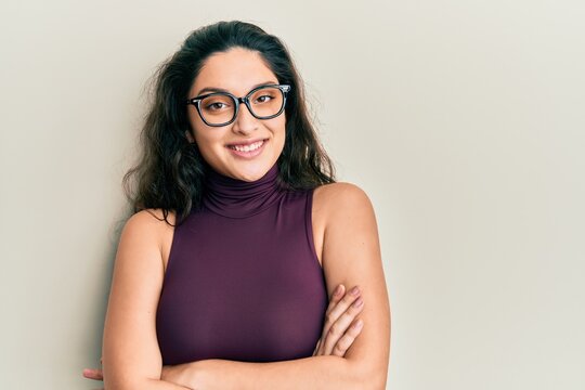 Beautiful middle eastern woman wearing casual clothes and glasses happy face smiling with crossed arms looking at the camera. positive person.