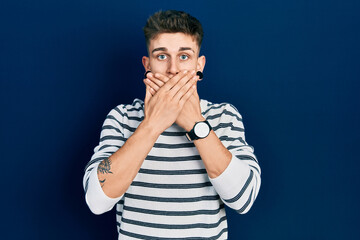 Young caucasian boy with ears dilation wearing casual striped shirt shocked covering mouth with hands for mistake. secret concept.