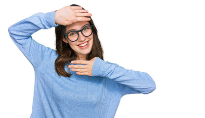 Young beautiful woman wearing casual clothes and glasses smiling cheerful playing peek a boo with hands showing face. surprised and exited